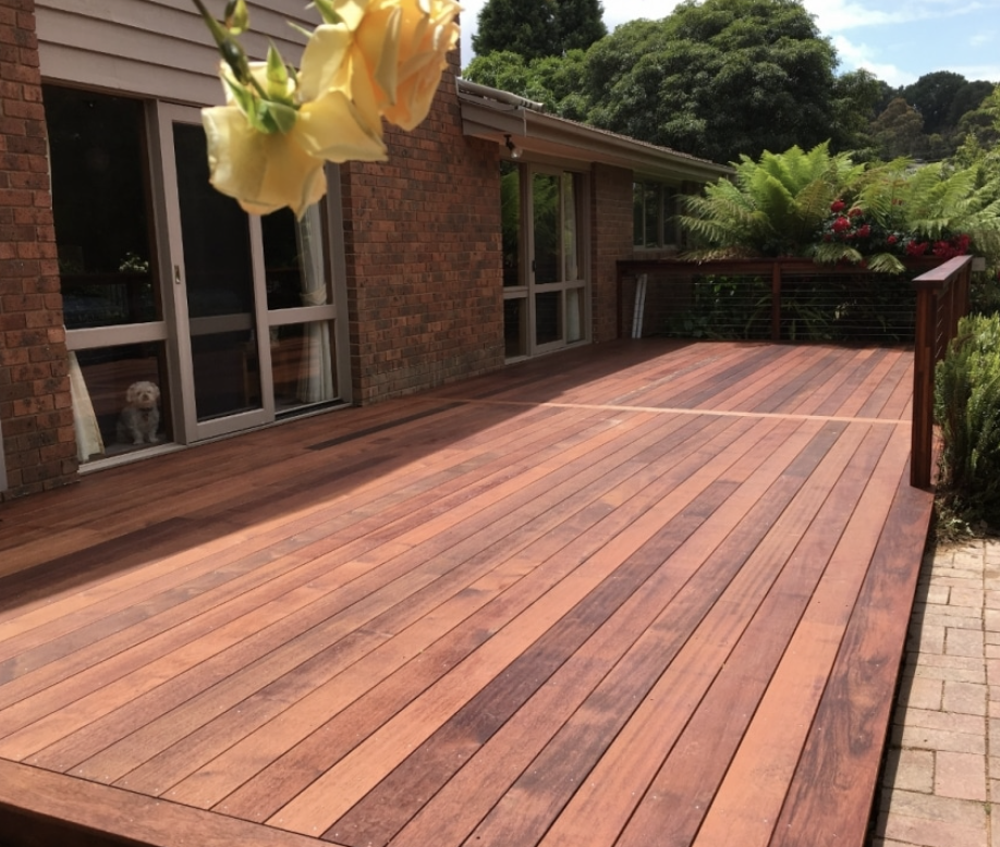 Custom-built wooden deck with modern steps and seating area near a brick house